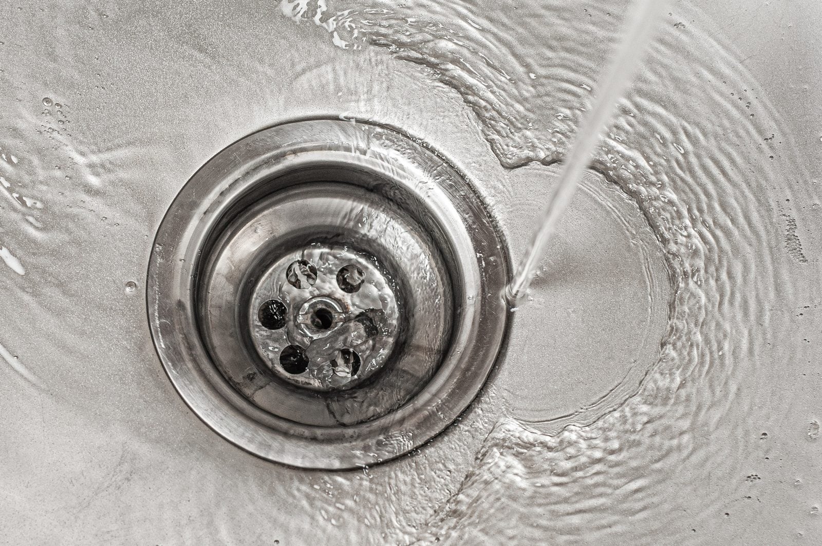 Water swirling into a stainless steel kitchen sink drain